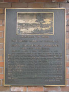 This plaque is attached to the outside of the west wall of the brick building on the south west corner of the square.  Click on the plaque to read what is written